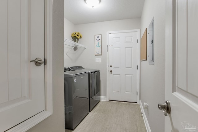 laundry area featuring a textured ceiling, light hardwood / wood-style flooring, and washing machine and clothes dryer