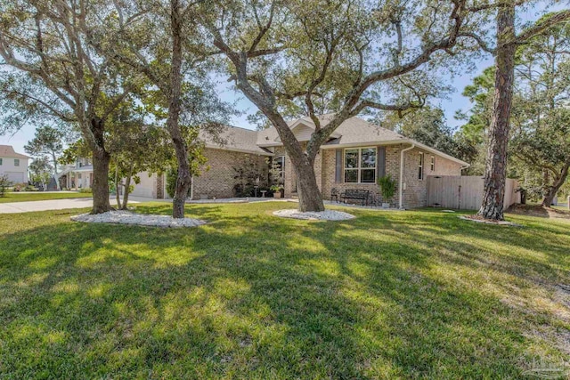 view of front facade with brick siding, fence, a garage, driveway, and a front lawn