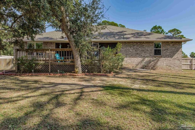 rear view of house featuring a wooden deck and a yard