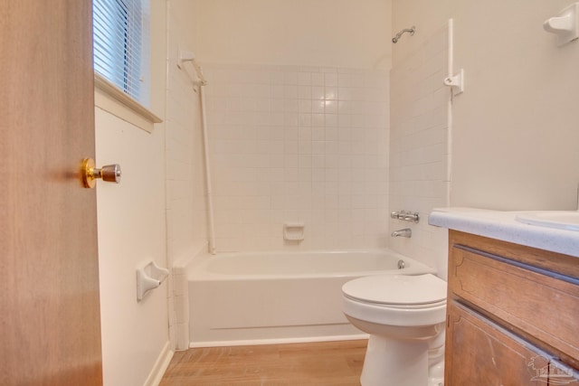 full bathroom featuring wood-type flooring, vanity, tiled shower / bath combo, and toilet