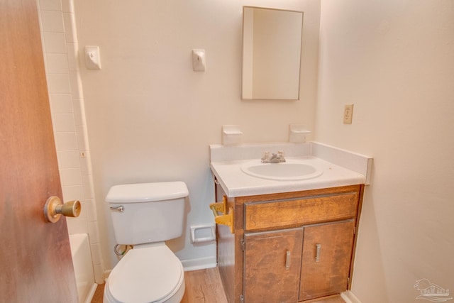 bathroom with wood-type flooring, a bath, vanity, and toilet