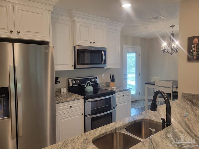 kitchen with white cabinetry, sink, light stone countertops, and appliances with stainless steel finishes