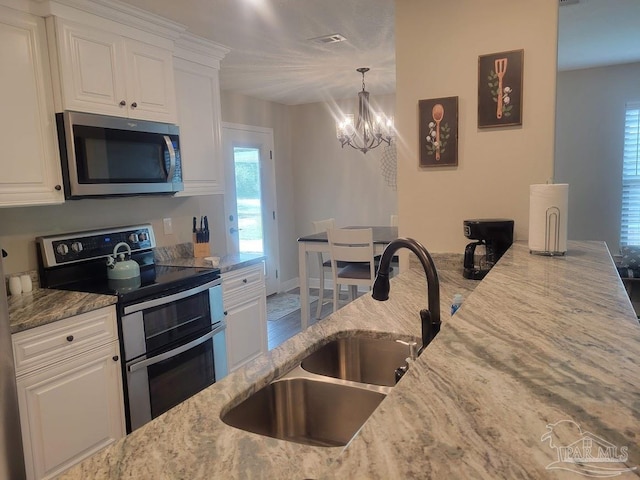 kitchen featuring white cabinetry, sink, light stone counters, appliances with stainless steel finishes, and hardwood / wood-style flooring