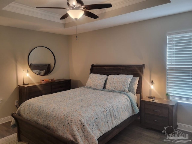 bedroom featuring dark hardwood / wood-style floors, ceiling fan, crown molding, and a tray ceiling