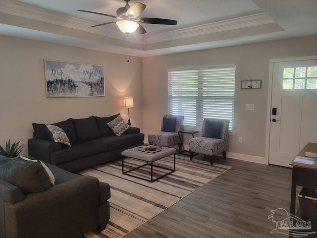 living room with a raised ceiling, ceiling fan, hardwood / wood-style floors, and crown molding