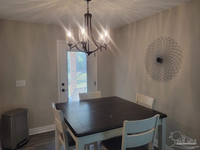 dining space with a textured ceiling, an inviting chandelier, and dark wood-type flooring