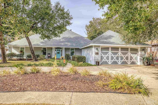 view of front of house with an outbuilding, a porch, a garage, a shingled roof, and driveway