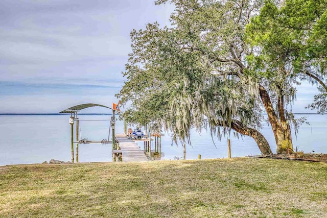 dock area with a water view, boat lift, and a lawn