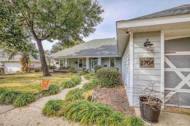 view of front of home with roof with shingles, a porch, and a front yard