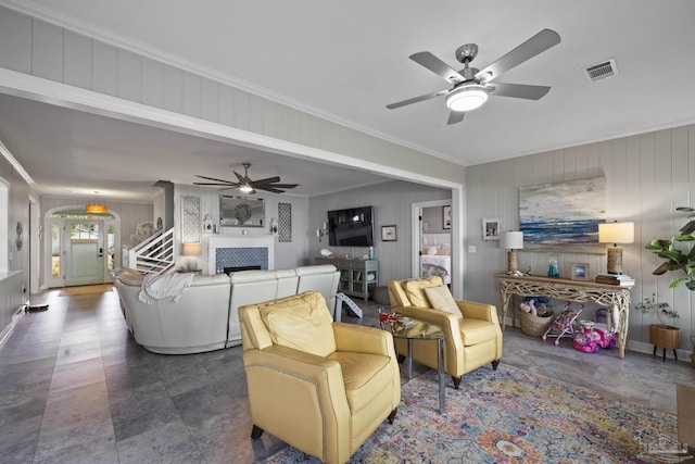 living room featuring ceiling fan, a tile fireplace, visible vents, and ornamental molding