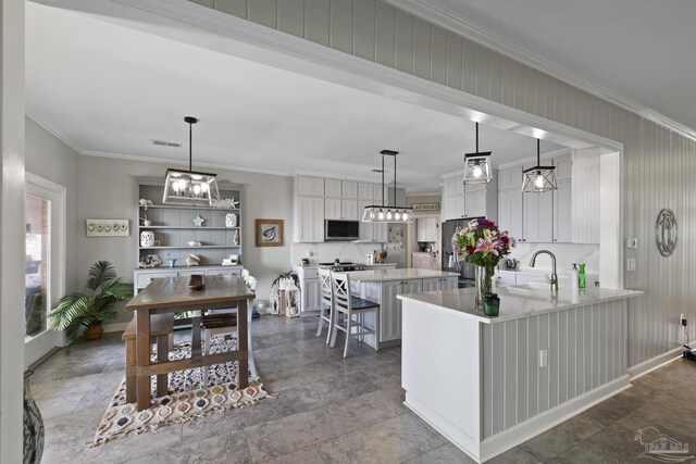 kitchen with appliances with stainless steel finishes, a sink, a breakfast bar, and crown molding