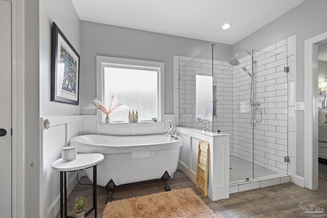 full bathroom featuring a freestanding tub, a shower stall, and wood finished floors