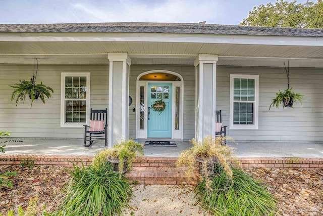 property entrance featuring a porch and roof with shingles