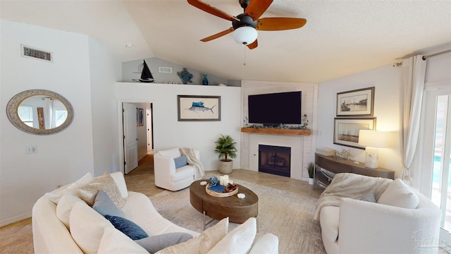 living area featuring vaulted ceiling, ceiling fan, a fireplace, and visible vents