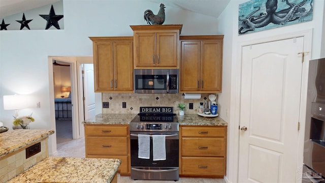 kitchen featuring light stone counters, lofted ceiling, backsplash, appliances with stainless steel finishes, and brown cabinetry