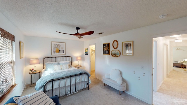 bedroom with a ceiling fan, baseboards, visible vents, and a textured ceiling