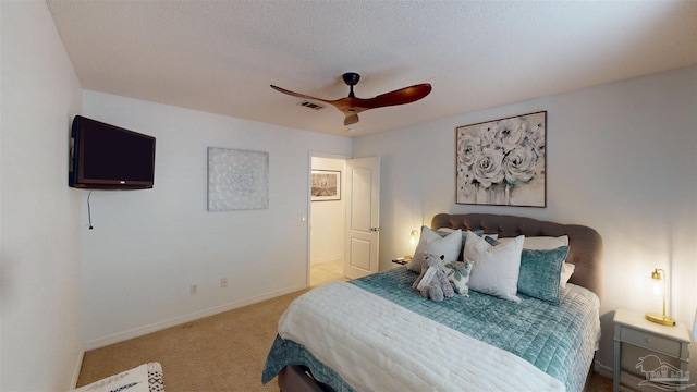 carpeted bedroom featuring ceiling fan, visible vents, baseboards, and a textured ceiling