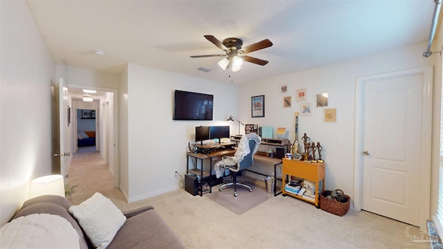 home office with baseboards, visible vents, a ceiling fan, and light colored carpet