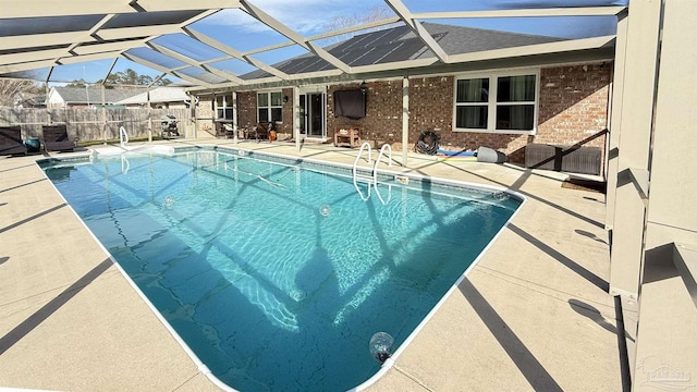 view of swimming pool with a patio, fence, a fenced in pool, and a lanai