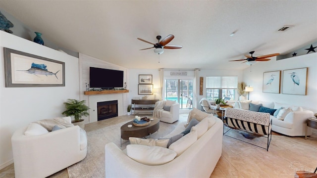 living room with a ceiling fan, a large fireplace, visible vents, and vaulted ceiling