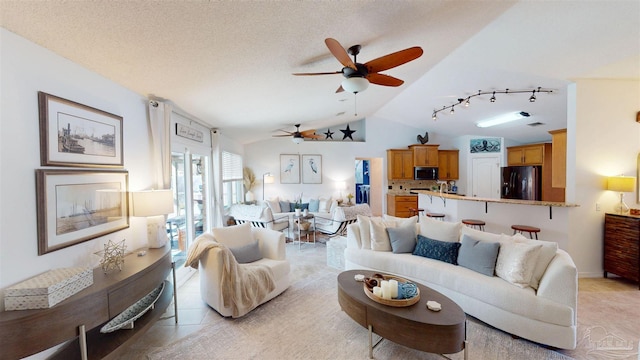 living area featuring a ceiling fan, vaulted ceiling, a textured ceiling, and track lighting