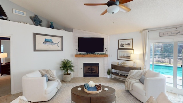 living room with vaulted ceiling, ceiling fan, and a fireplace