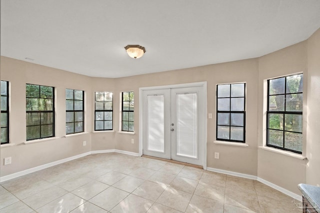 tiled empty room featuring french doors and a healthy amount of sunlight