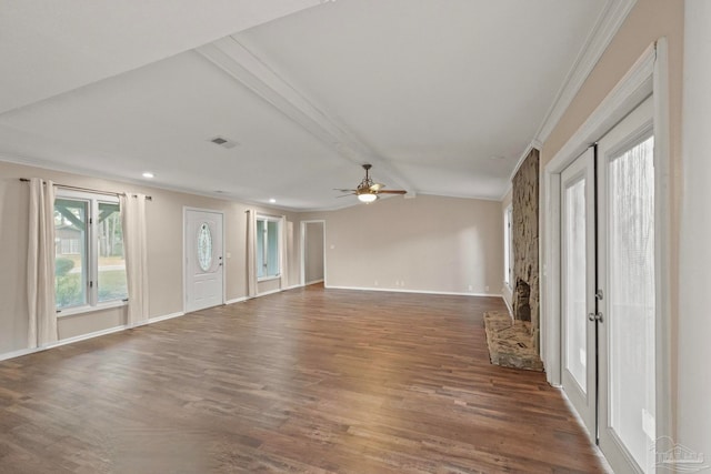 empty room featuring a stone fireplace, dark hardwood / wood-style floors, crown molding, lofted ceiling with beams, and ceiling fan