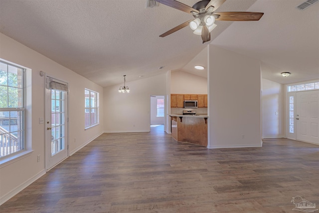 unfurnished living room with vaulted ceiling, dark wood-type flooring, a textured ceiling, and visible vents