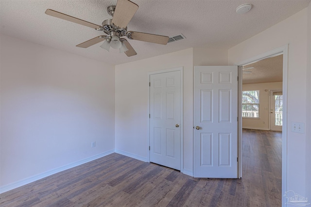 unfurnished bedroom featuring visible vents, a textured ceiling, baseboards, and wood finished floors