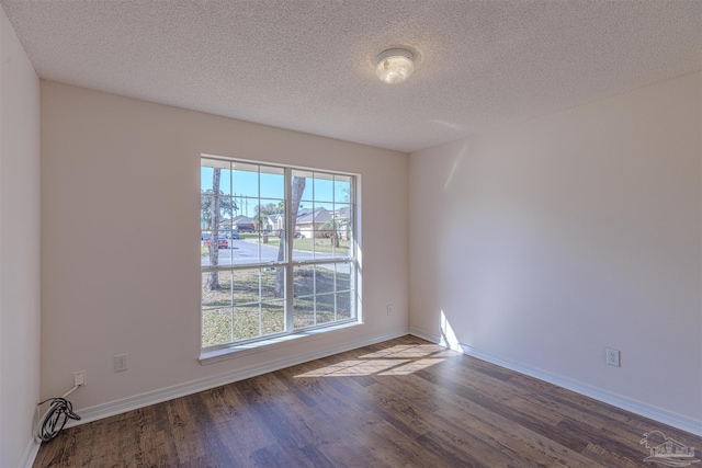 unfurnished room with a textured ceiling, baseboards, and wood finished floors