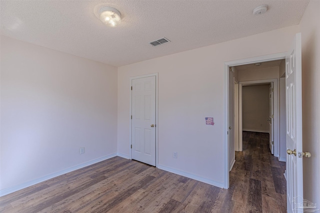 unfurnished bedroom with baseboards, a textured ceiling, visible vents, and wood finished floors