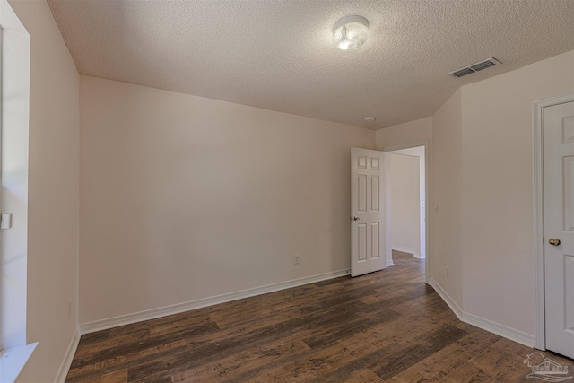 unfurnished room with baseboards, visible vents, dark wood finished floors, and a textured ceiling