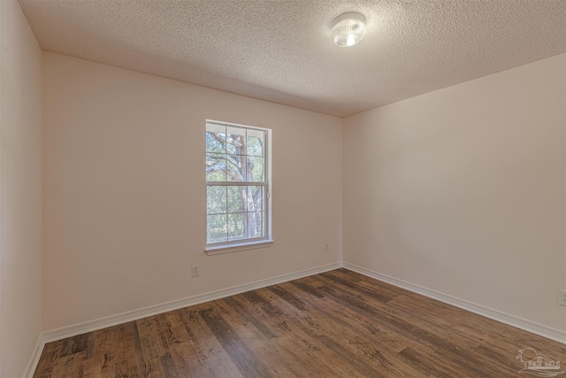 unfurnished room featuring a textured ceiling, dark wood finished floors, and baseboards