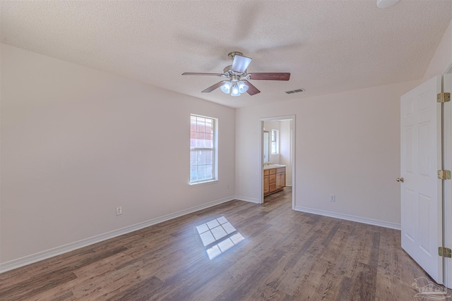 unfurnished room with dark wood-style floors, a textured ceiling, visible vents, and baseboards