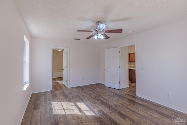 unfurnished bedroom featuring a textured ceiling, wood finished floors, visible vents, and baseboards