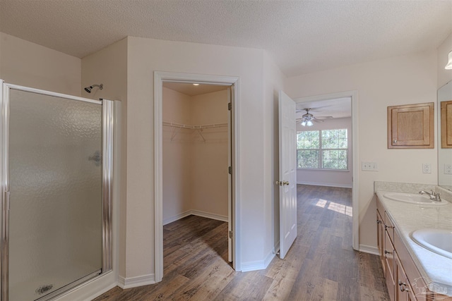 bathroom with double vanity, wood finished floors, a stall shower, and a sink