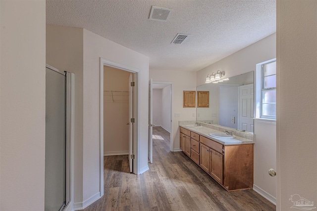 full bath with double vanity, wood finished floors, a sink, and visible vents