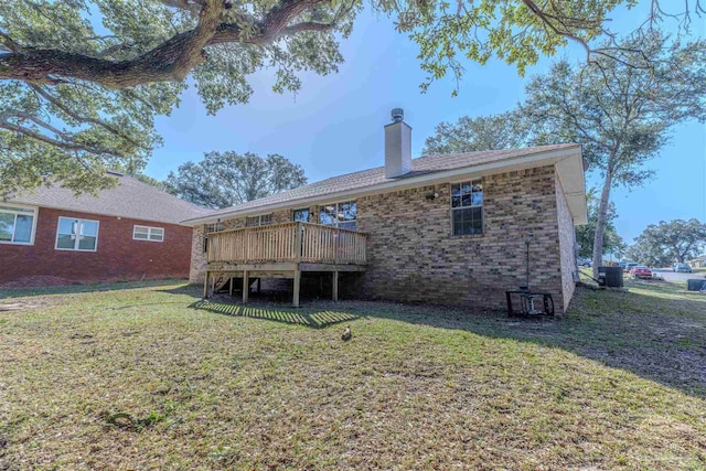 back of house with a chimney, a deck, a lawn, and brick siding