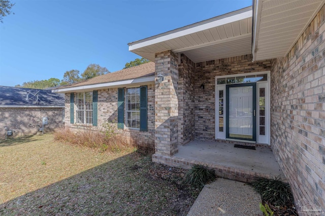 property entrance featuring a yard and brick siding