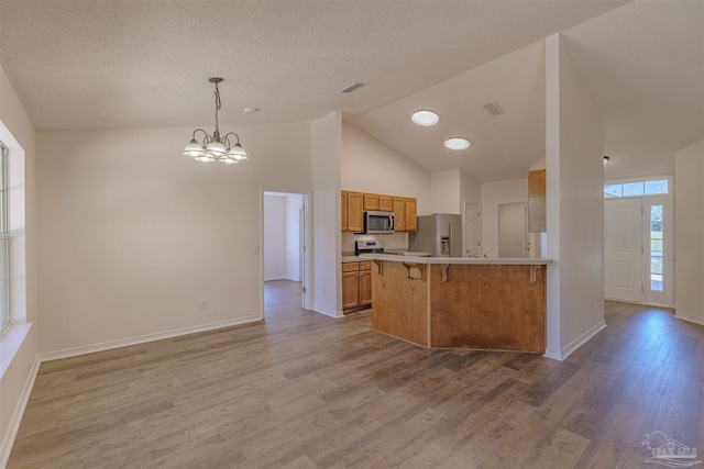 kitchen featuring a peninsula, light wood-style floors, appliances with stainless steel finishes, and a breakfast bar