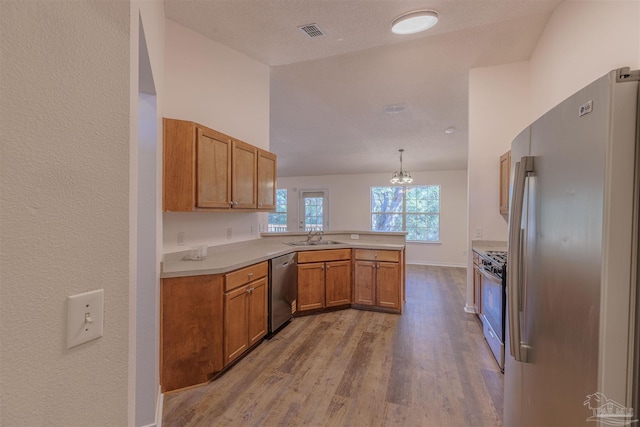 kitchen with visible vents, appliances with stainless steel finishes, brown cabinets, a peninsula, and light countertops