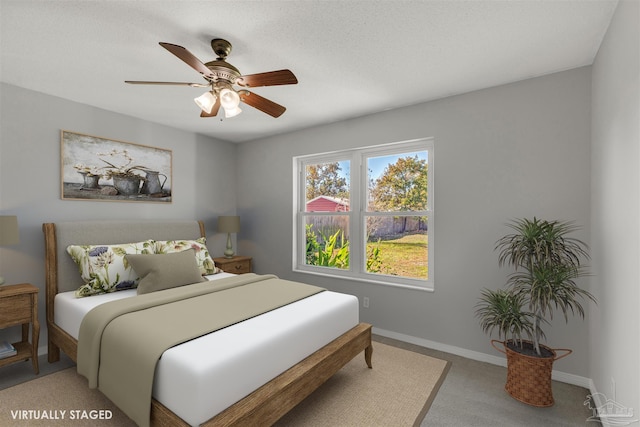 carpeted bedroom featuring ceiling fan and a textured ceiling