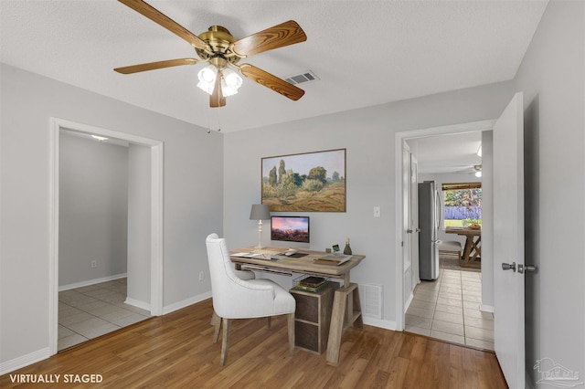 office space featuring a textured ceiling, light wood-type flooring, and ceiling fan