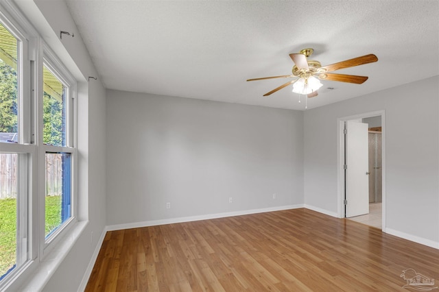 empty room with a textured ceiling, light hardwood / wood-style floors, plenty of natural light, and ceiling fan