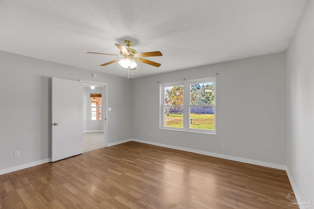 spare room featuring ceiling fan, light hardwood / wood-style flooring, and a textured ceiling