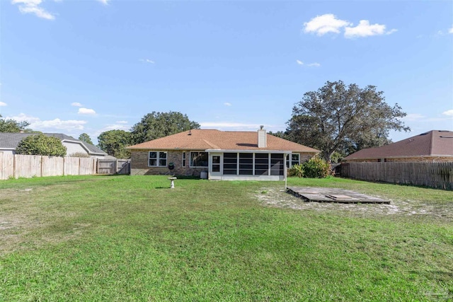 rear view of house featuring a lawn and a sunroom