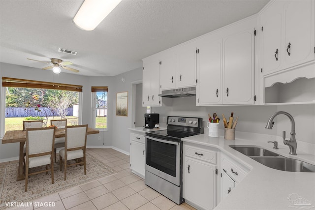 kitchen featuring sink, ceiling fan, stainless steel electric range oven, light tile patterned flooring, and white cabinetry