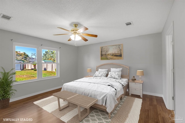 bedroom with a textured ceiling, ceiling fan, and dark hardwood / wood-style floors