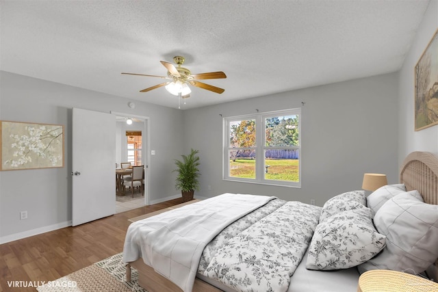 bedroom featuring a textured ceiling, light wood-type flooring, and ceiling fan